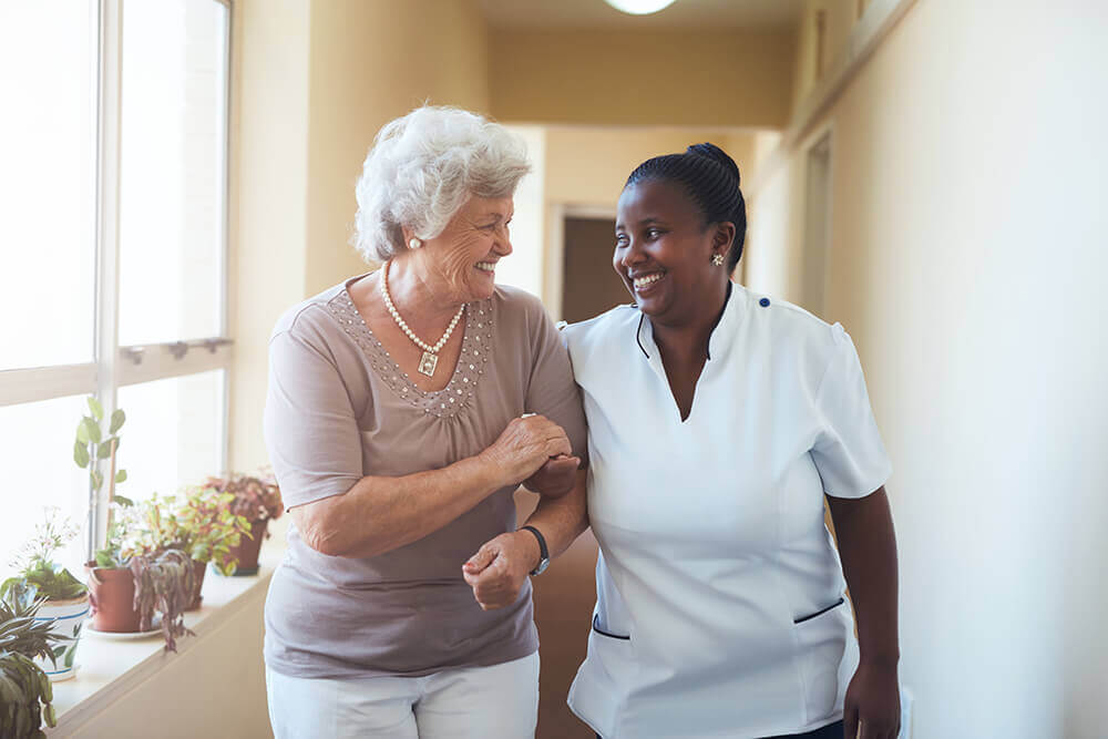 Senior Resident and Caregiver Walking Arm and Arm